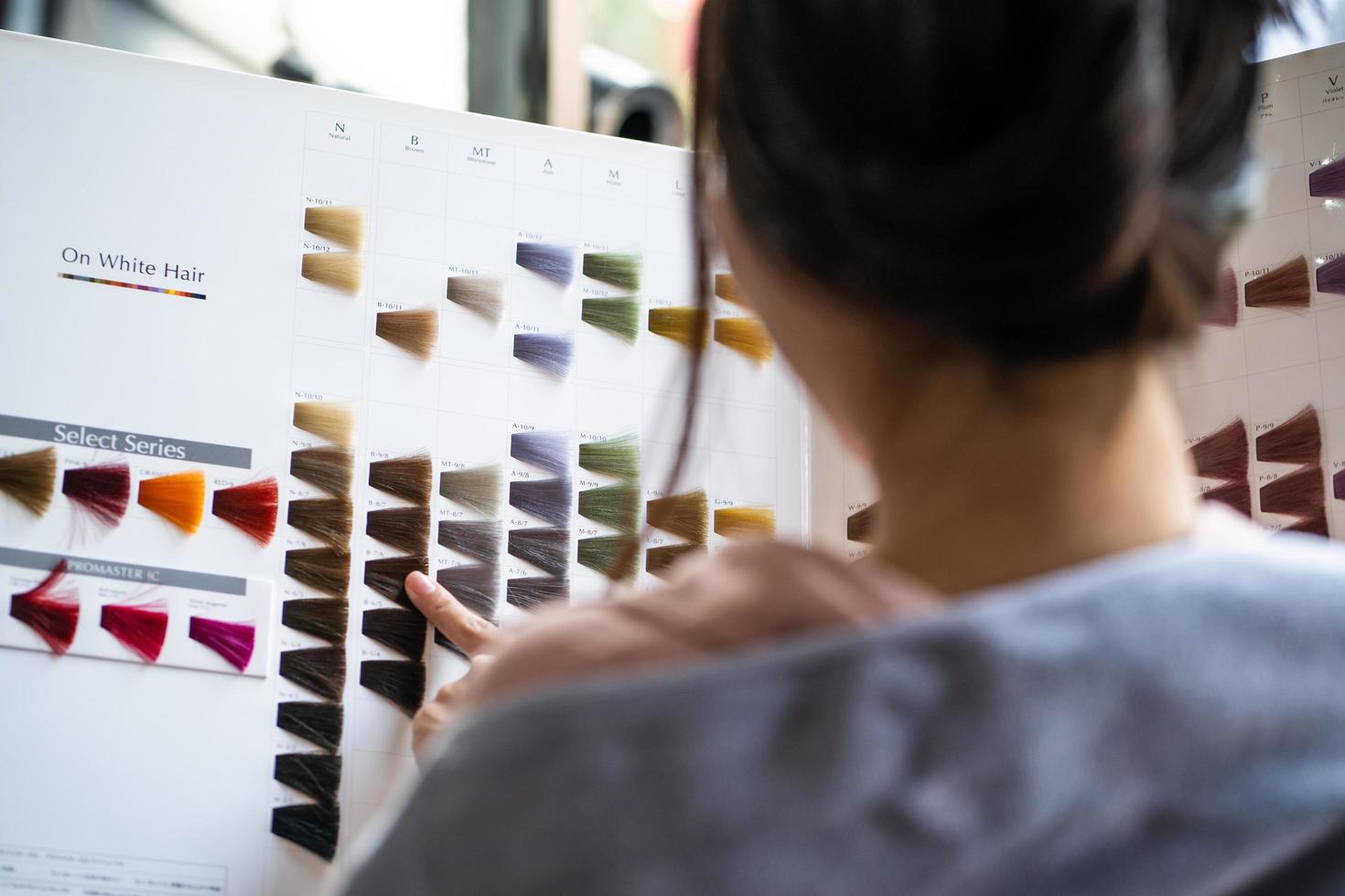 focus sur le nuancier. jeunes jolies femmes asiatiques assises à l'intérieur d'un salon de coiffure, souriantes tout en choisissant une nouvelle couleur et un nouveau style de teinture capillaire dans la sélection du nuancier. mode de beauté féminine, concept de soins personnels photo