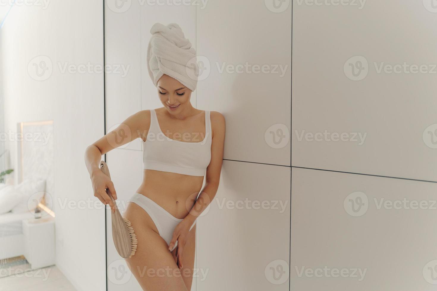 belle jeune femme debout dans la salle de bain avec une brosse en bois pour le massage photo