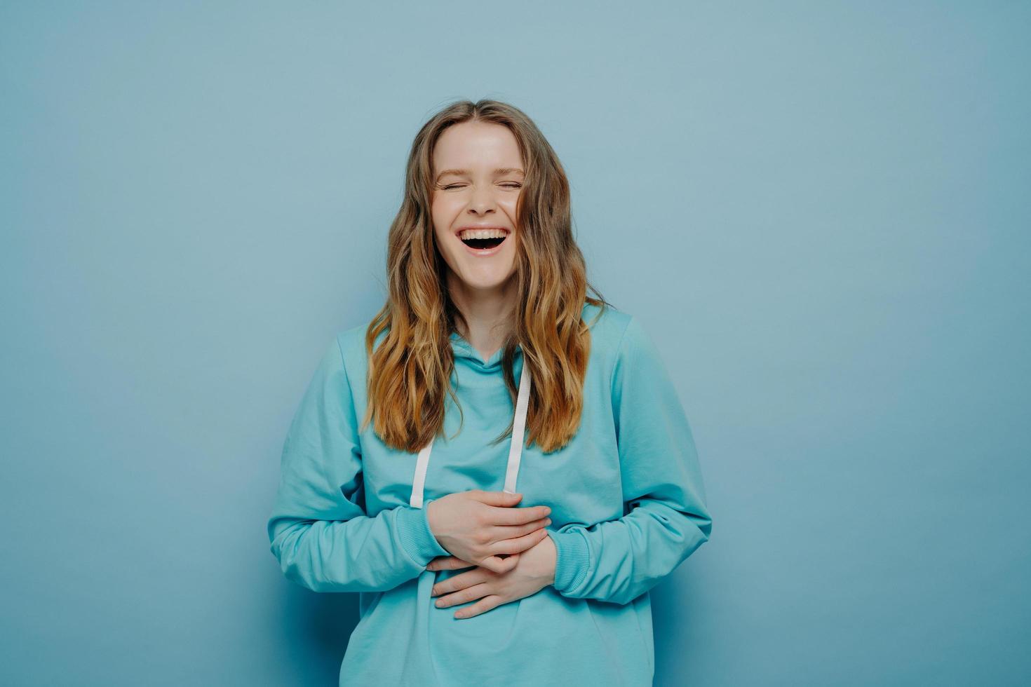 femme riante avec les mains sur le ventre posant en studio photo