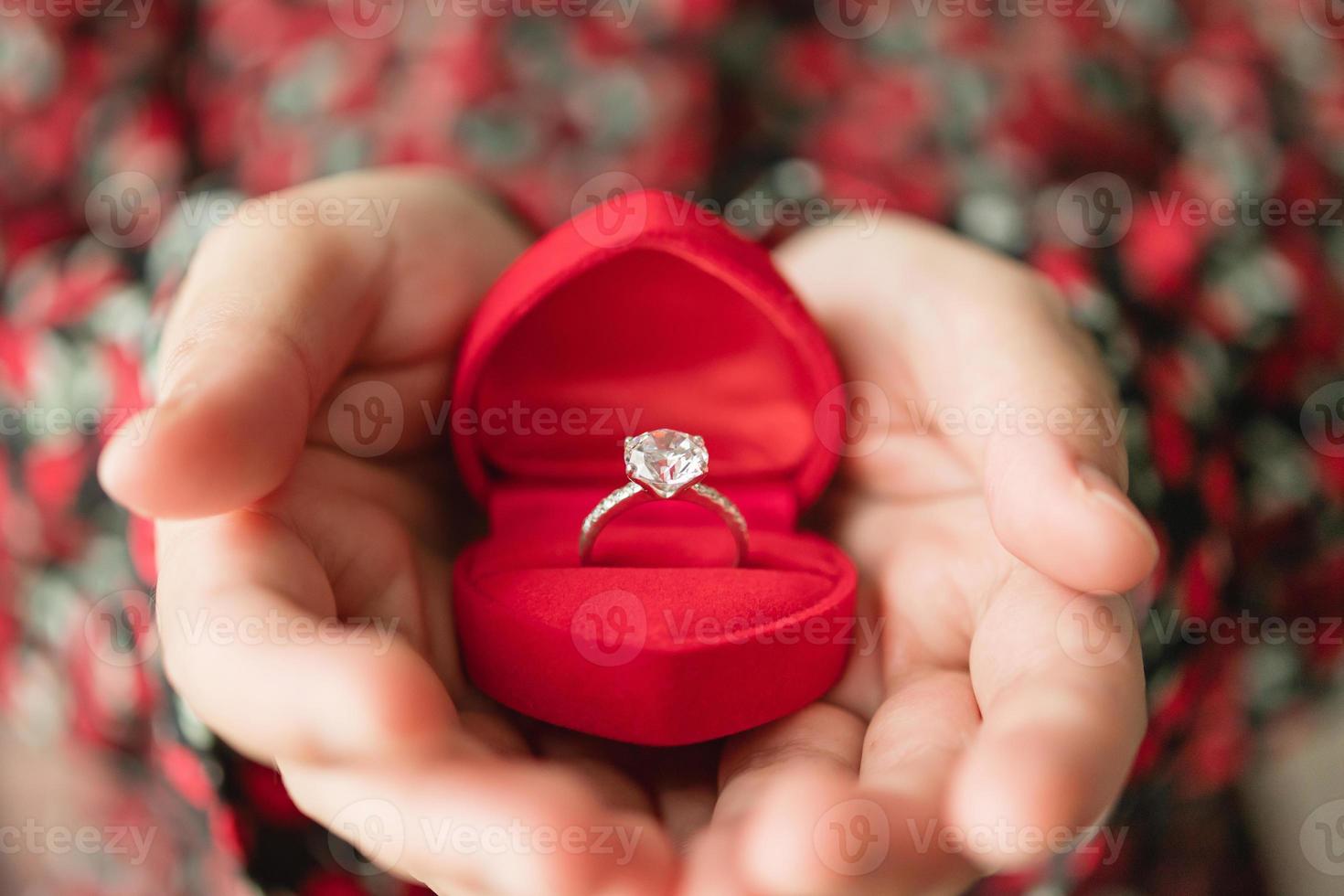 mains tenant une bague en diamant dans une boîte à bijoux photo