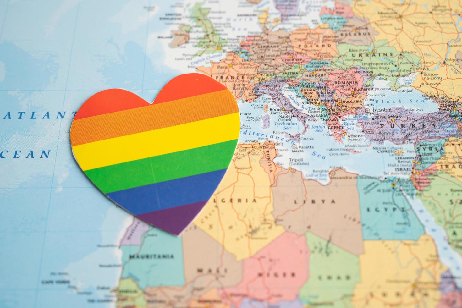 coeur de couleur arc-en-ciel sur fond de carte du monde globe, symbole du mois de la fierté lgbt célèbre annuellement en juin social, symbole des gays, lesbiennes, bisexuels, transgenres, droits de l'homme et paix. photo