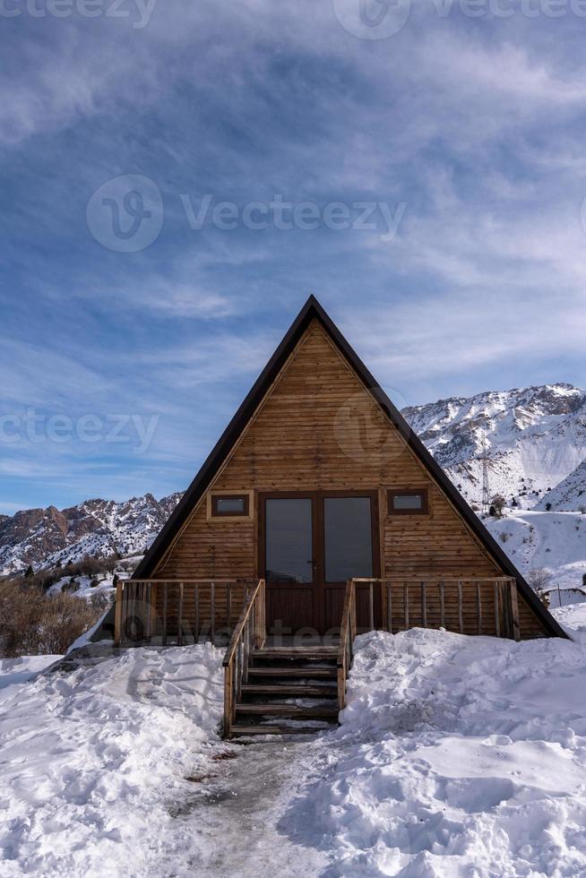 une photo verticale d'un chalet en bois entouré de neige. une aire de loisirs à la montagne