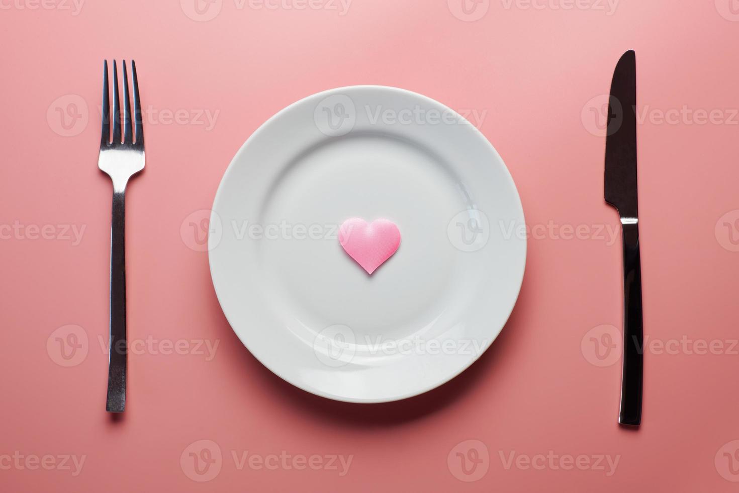 en attente d'un plat préféré au restaurant ou au café. coeur sur assiette avec fourchette et couteau. amoureux réunis lors d'un déjeuner quotidien. photo