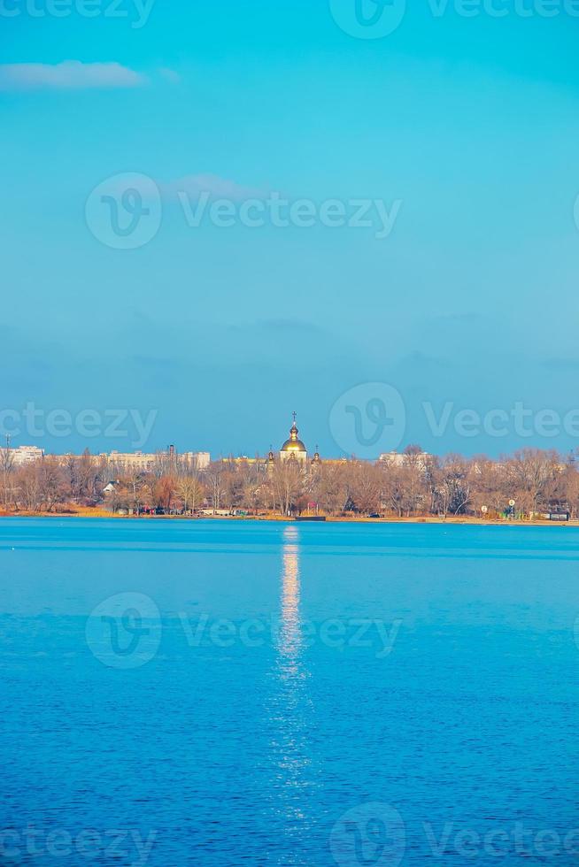 la coupole dorée de l'église orthodoxe, dressée sur les rives du fleuve, se reflète à la surface de l'eau. passerelle dorée du dôme de l'église à la surface de la rivière. photo