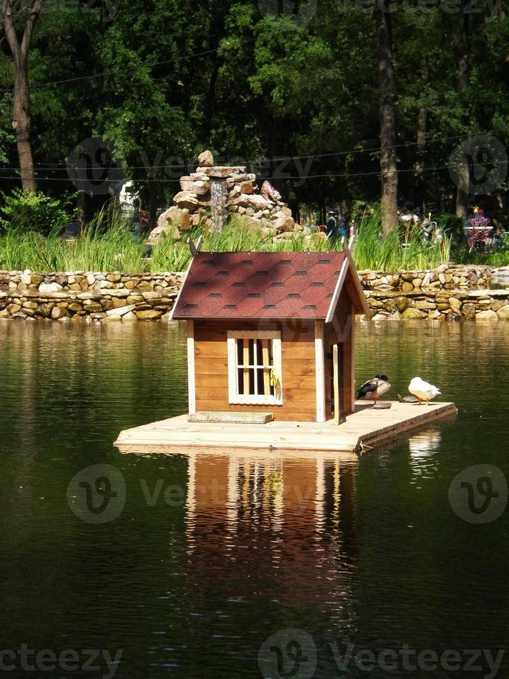 étang avec maison d'oiseau sur fond de toboggan alphine dans le parc gorky,melitopol photo