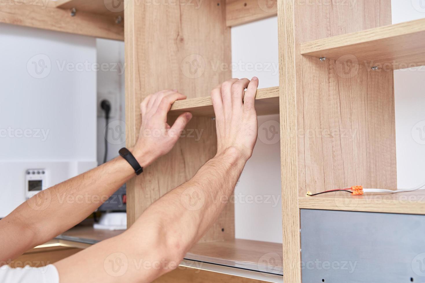 Un charpentier masculin installe une étagère dans une armoire de cuisine photo