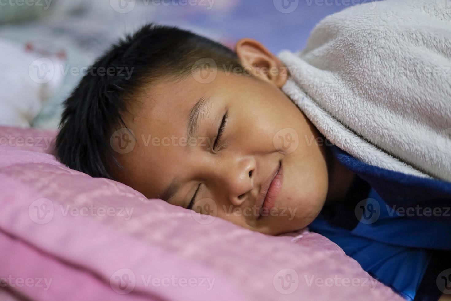 garçon asiatique dort bien sur le matelas et la couverture dans sa chambre. beaux rêves photo