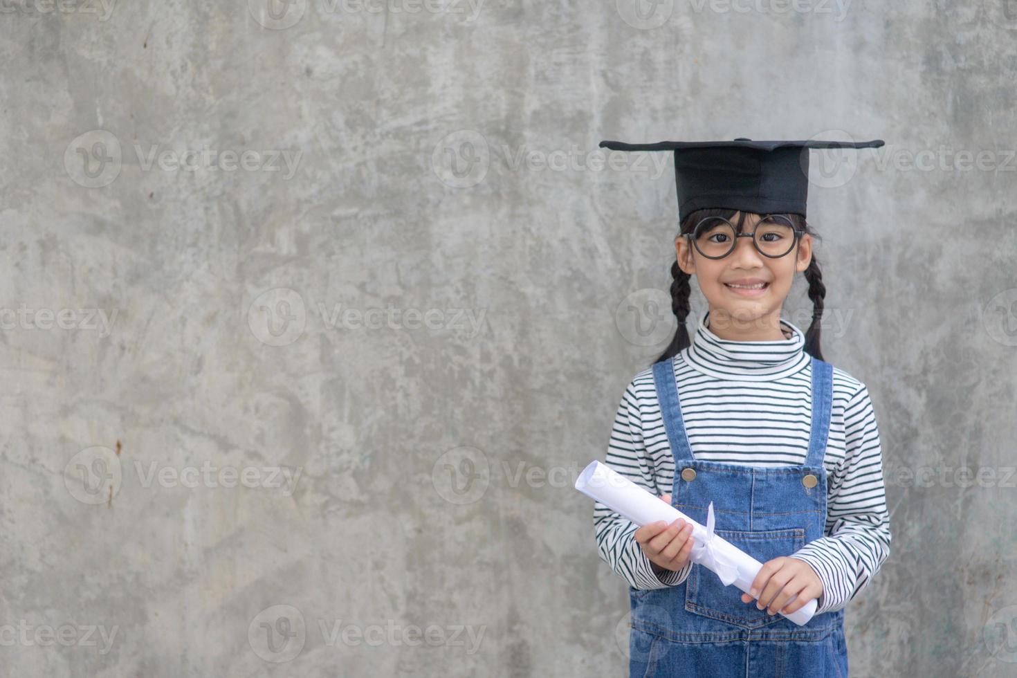 heureux écolier asiatique diplômé en chapeau de graduation photo