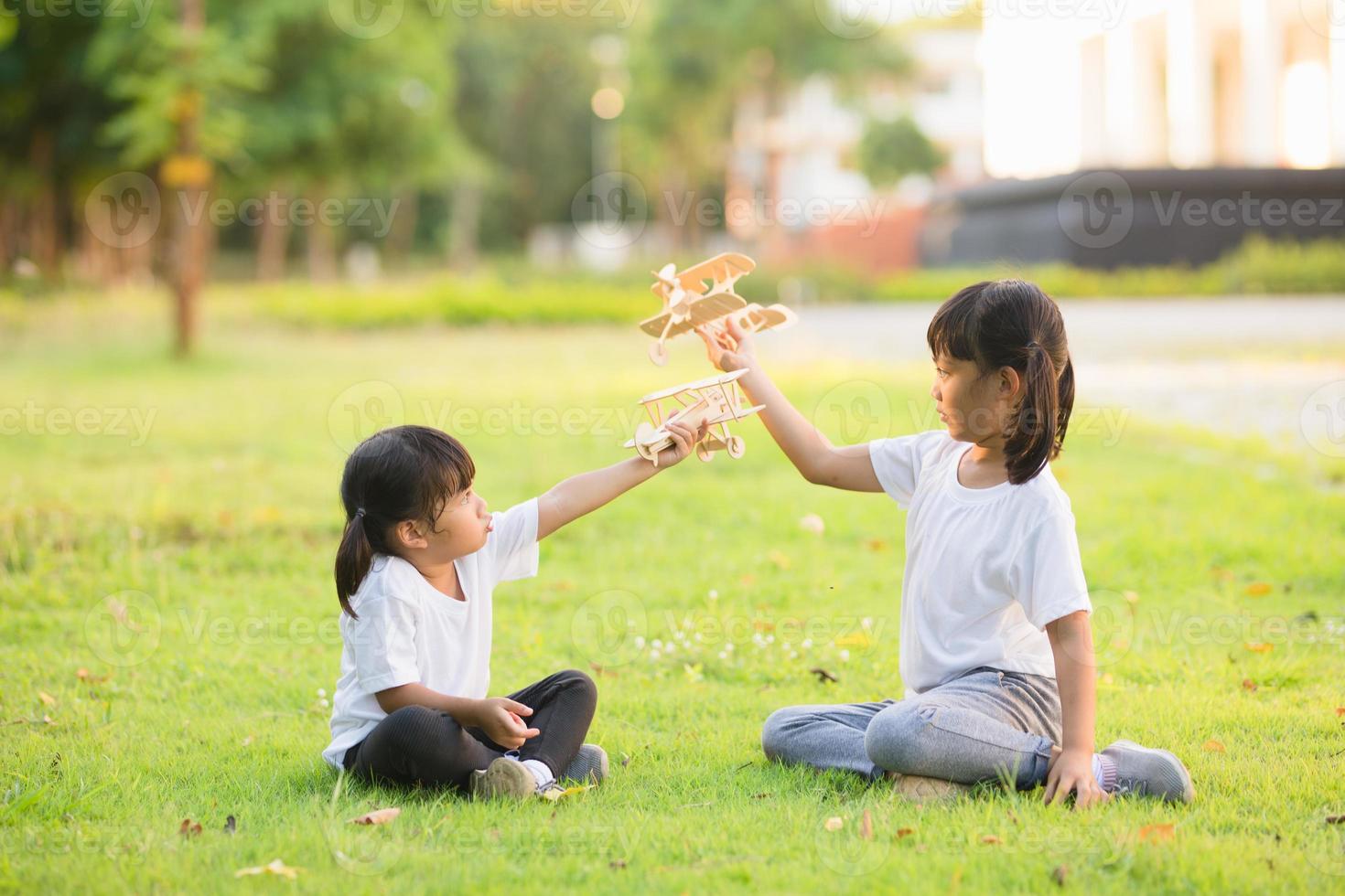 deux petits enfants jouant avec un avion jouet en carton dans le parc pendant la journée. concept de jeu heureux. enfant s'amusant à l'extérieur. photo
