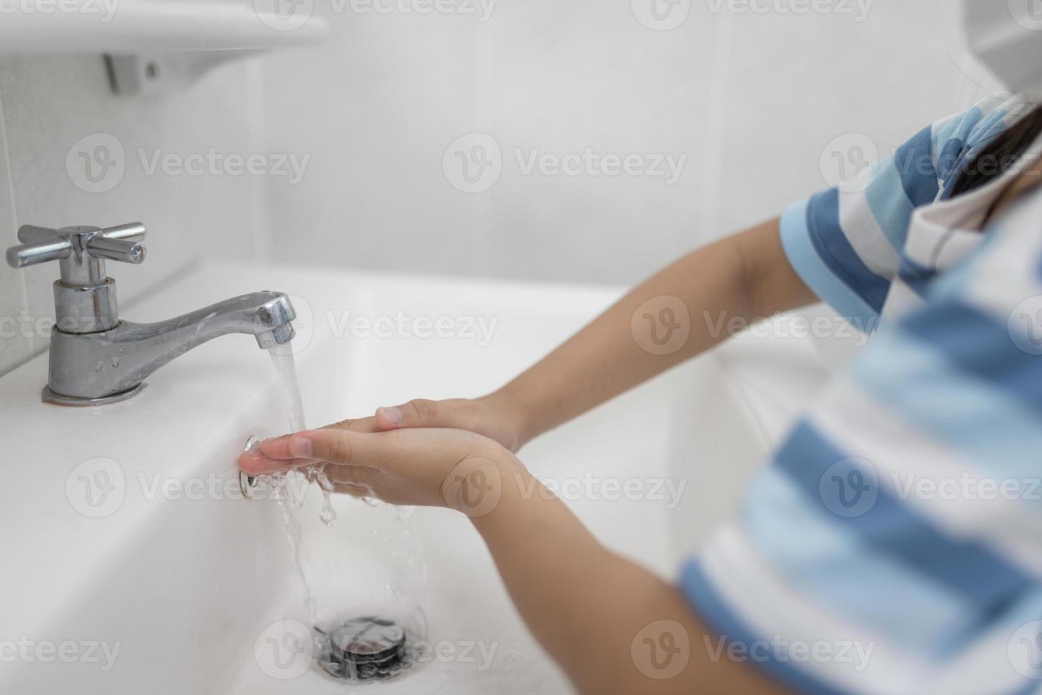 les petites filles asiatiques se lavent les mains dans la salle de bain. mise au point douce. espace de copie. photo