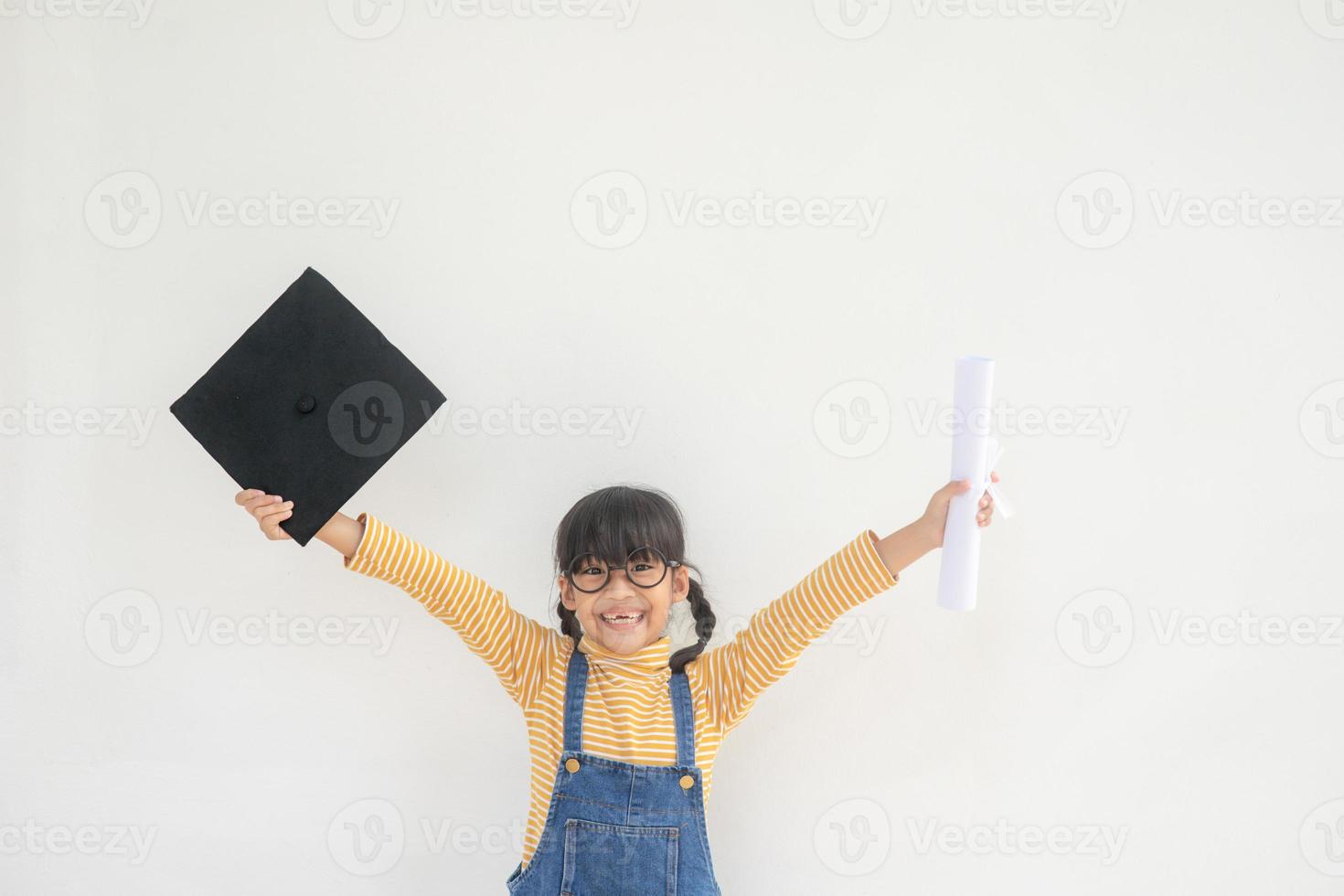 enfants fille portant une casquette de diplômé sur fond blanc très heureux et excité faisant le geste du gagnant avec les bras levés, souriant et criant pour le succès. notion de célébration. photo