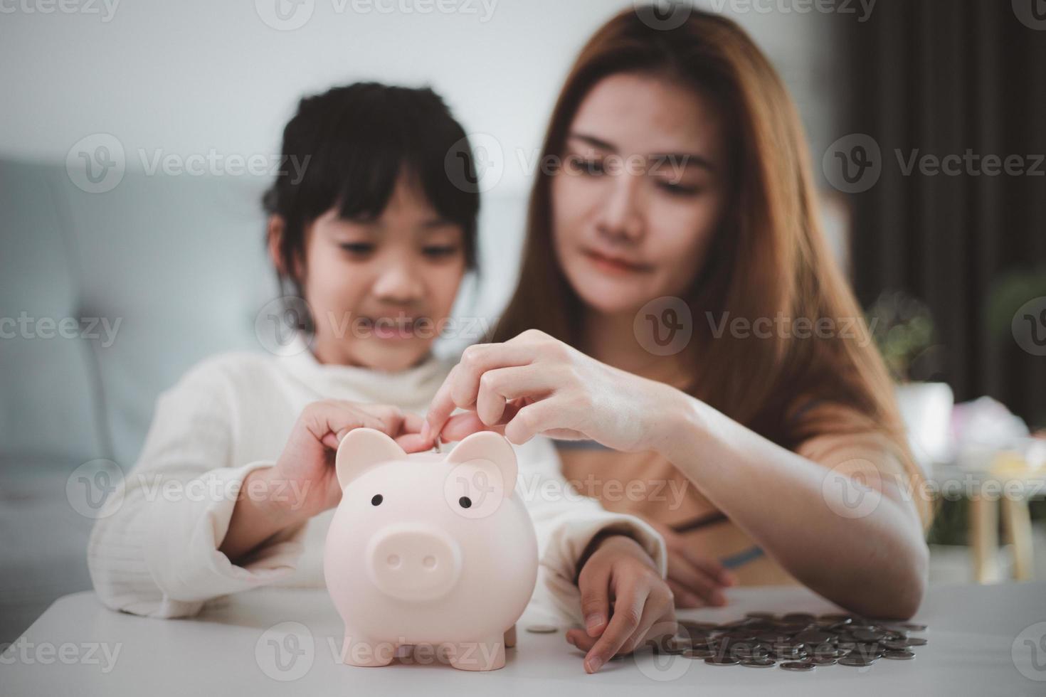 l'épargne familiale. mère enseignant à sa petite fille comment économiser de l'argent en tenant une tirelire photo