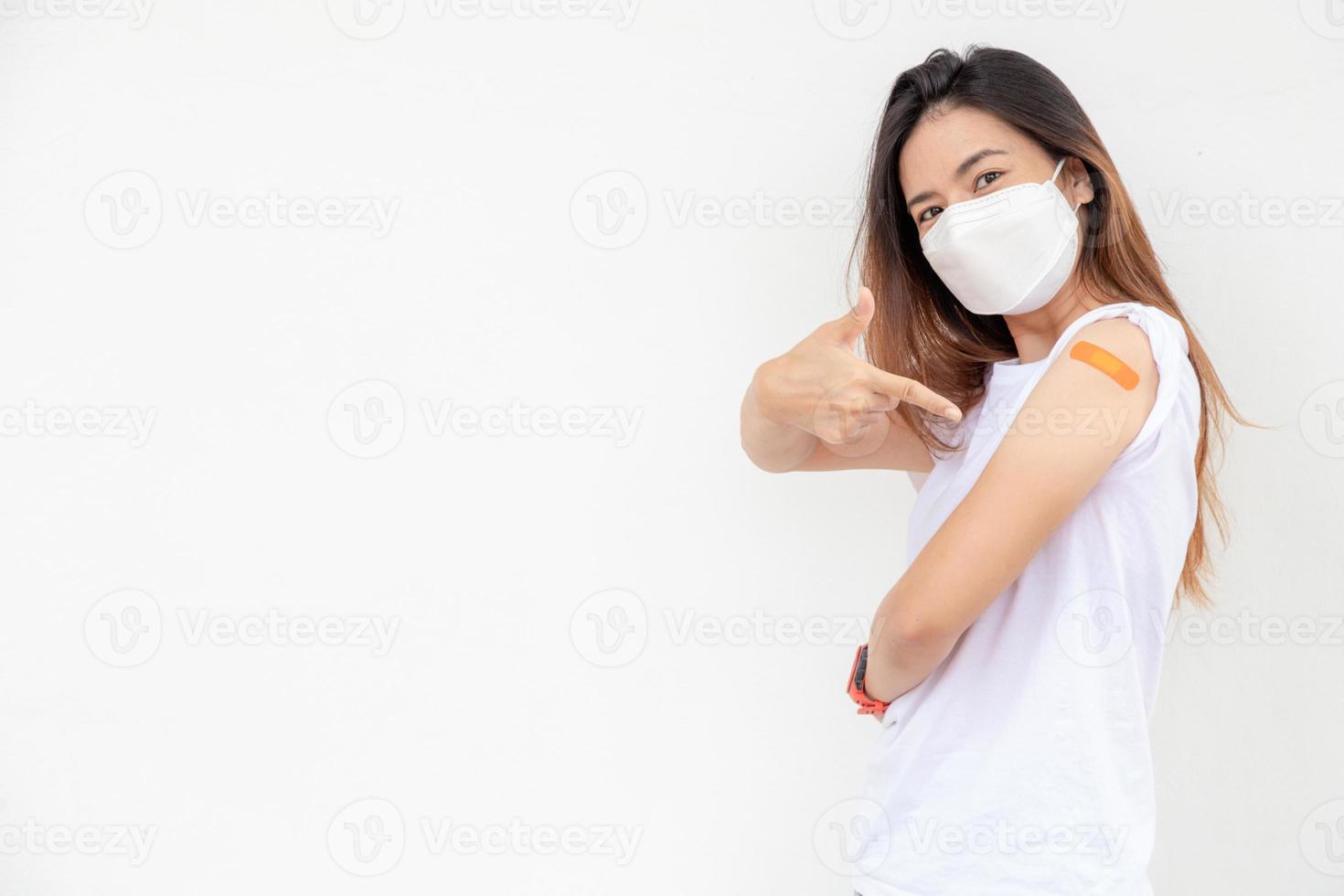 les femmes asiatiques montrent un bandage sur le bras. une femme asiatique heureuse se sent bien après avoir reçu le vaccin sur fond blanc. photo