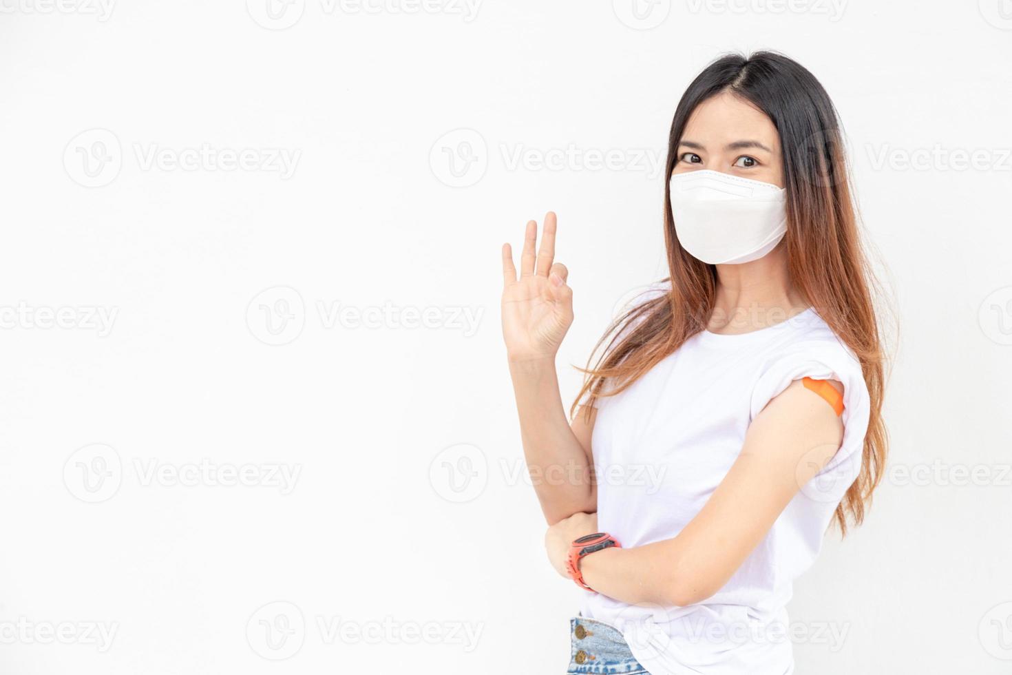 les femmes asiatiques montrent un bandage sur le bras. une femme asiatique heureuse se sent bien après avoir reçu le vaccin sur fond blanc. photo