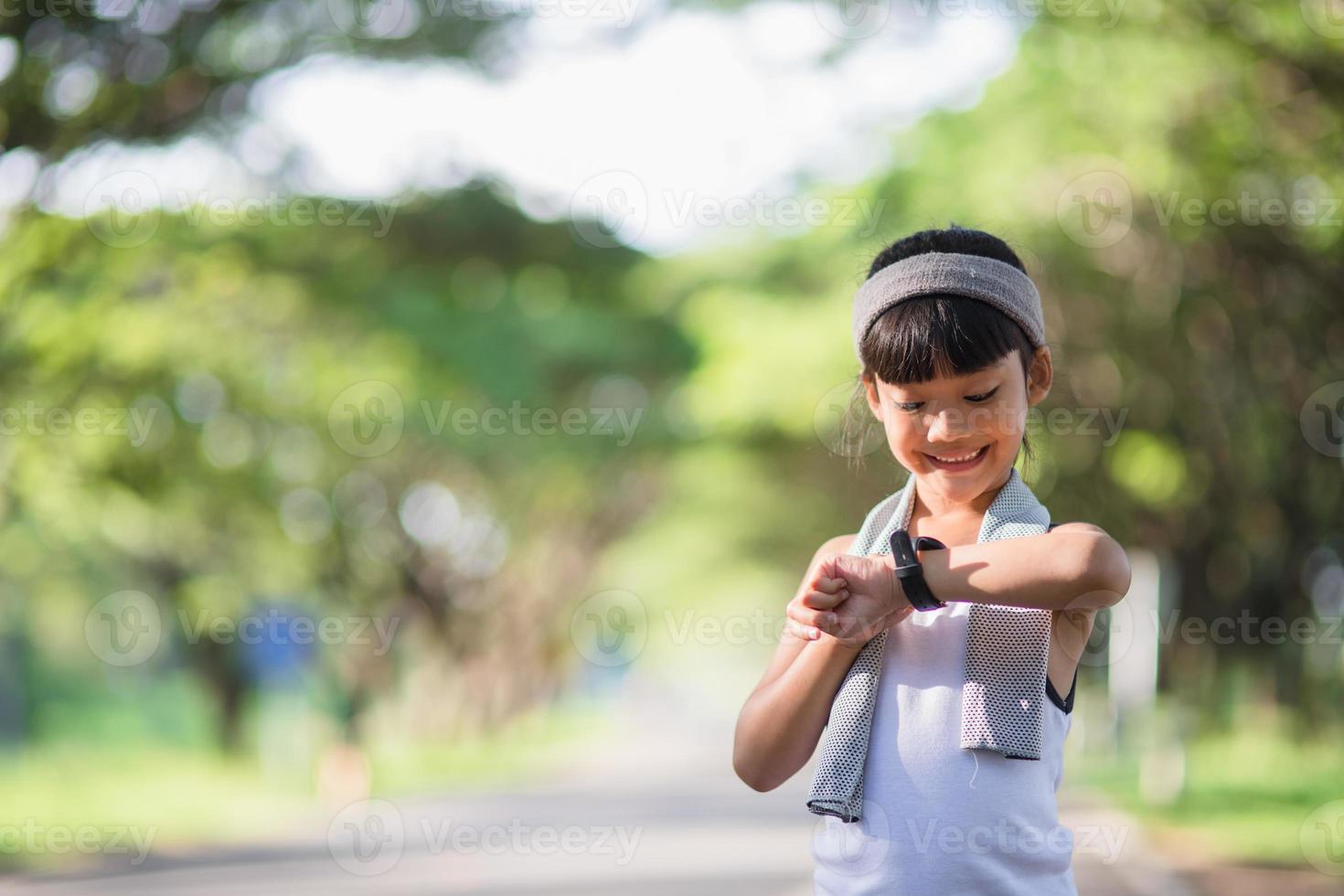 fille enfant heureuse qui court dans le parc en été dans la nature. lumière du soleil chaude. le petit asiatique court dans un parc. sports de plein air et fitness, apprentissage de l'exercice et de la compétition pour le développement des enfants. photo