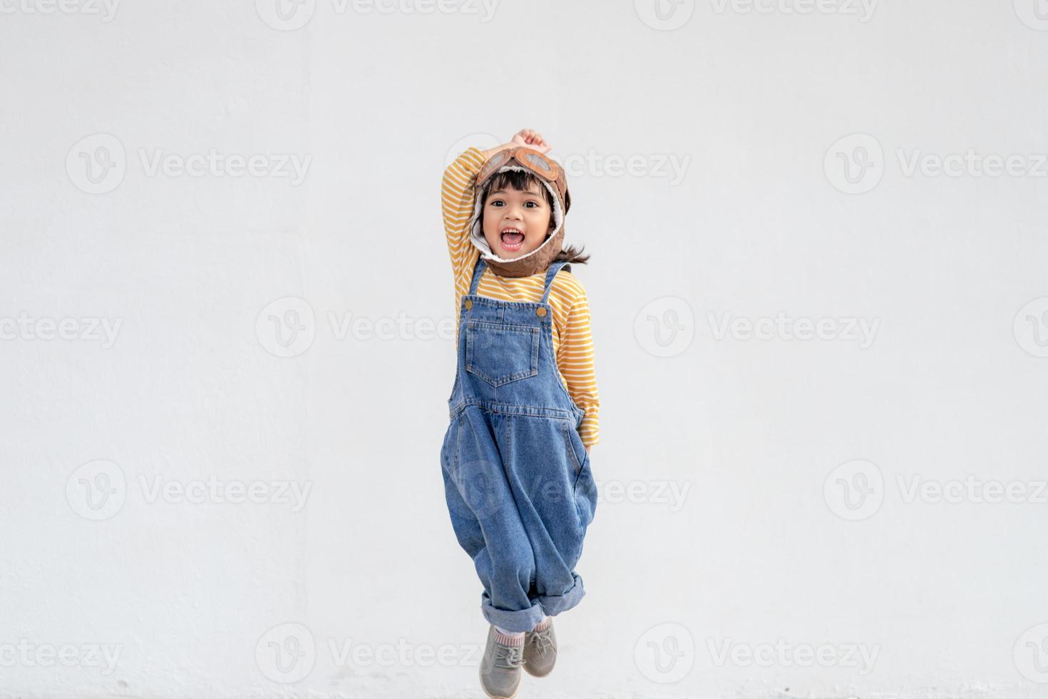 une jolie petite fille vêtue d'une casquette et de lunettes de pilote. l'enfant rêve de devenir pilote. photo