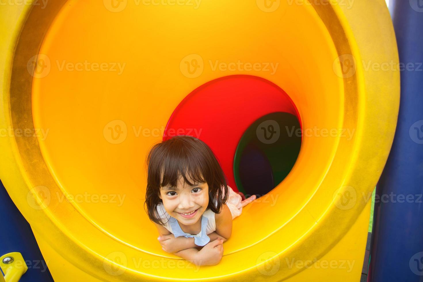 petites filles heureuses regardant la caméra dans le tunnel sur l'aire de jeux. photo