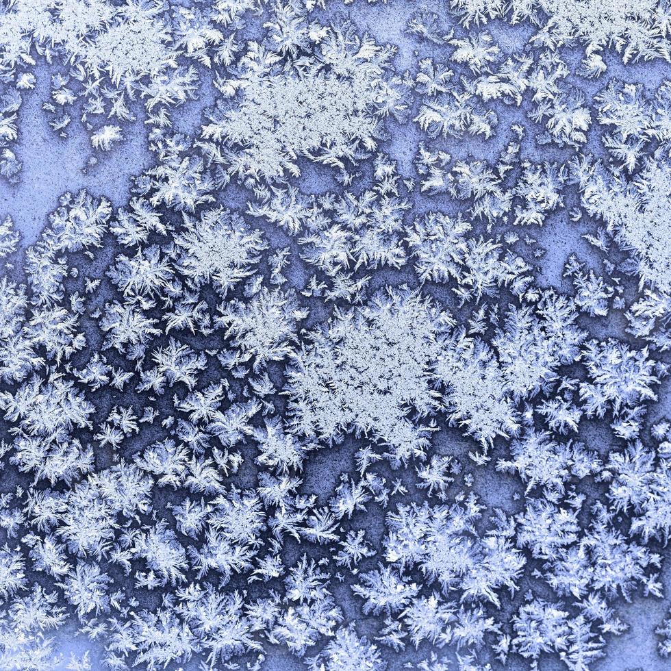 flocons de neige et givre sur la fenêtre gelée en hiver photo