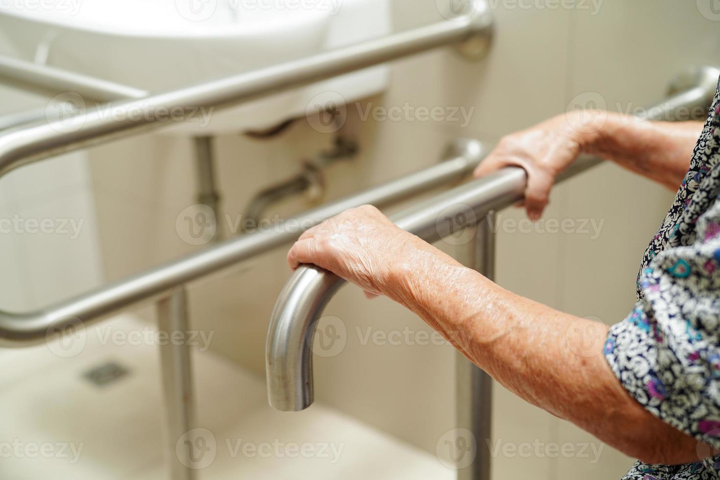 une vieille femme asiatique âgée utilise un rail de support de toilette dans la salle de bain, une barre d'appui de sécurité pour main courante, la sécurité dans l'hôpital de soins infirmiers. photo