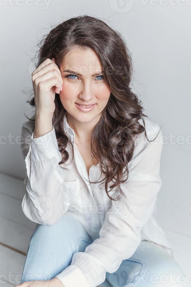 fille dans une pièce lumineuse assise contre un mur blanc photo