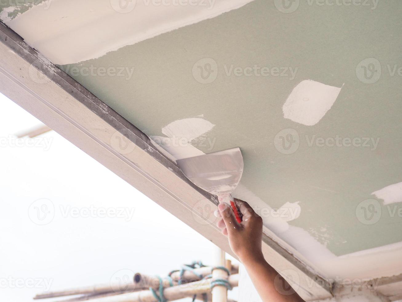 le plafonnier enduit les joints du plafond avec du plâtre de gypse blanc de haute qualité pour maintenir les joints ensemble. photo