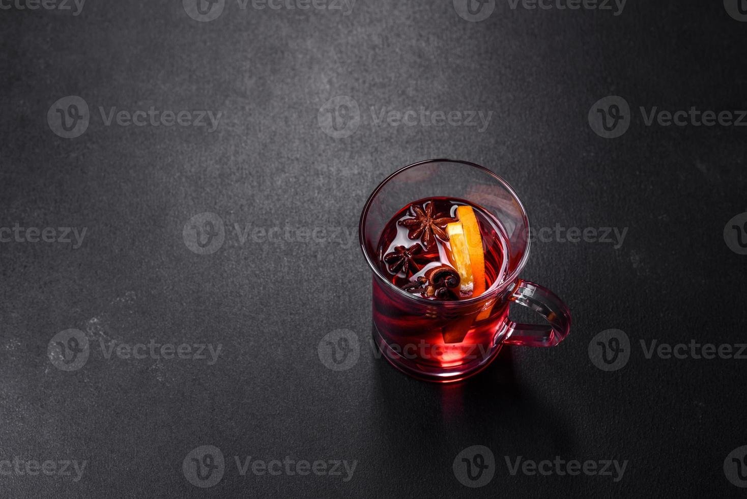 vin rouge chaud de noël avec des épices et des fruits sur une table en béton photo