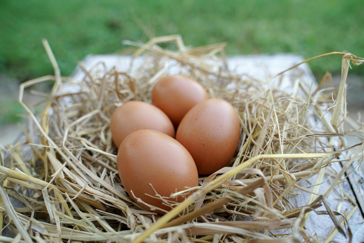 oeufs de poule frais sur paille sèche et table en bois dans une ferme de village rural en thaïlande. photo