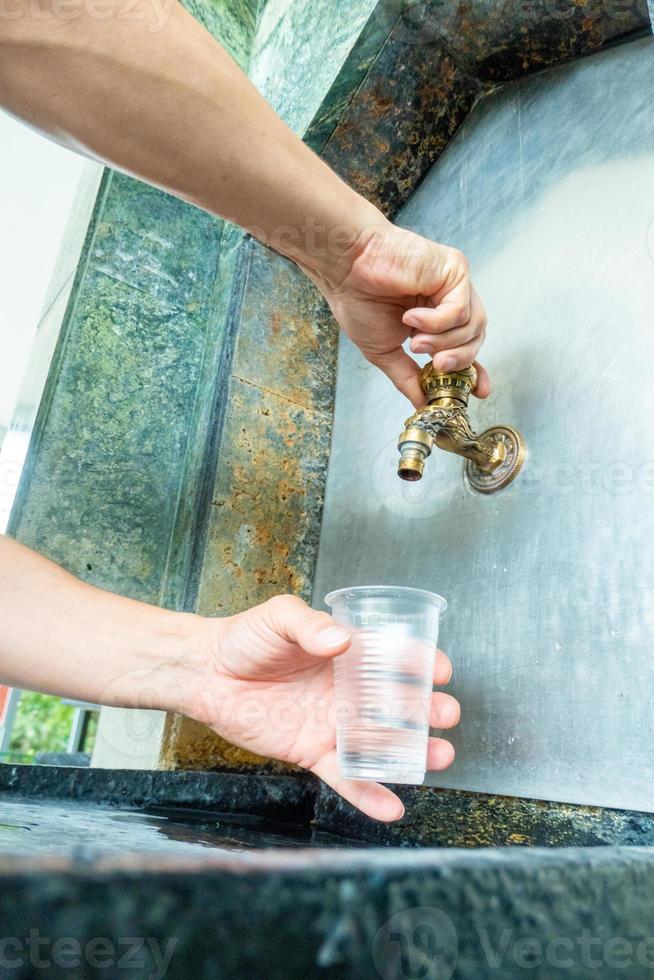 verser de l'eau thermale minérale dans le gobelet jetable de la salle des pompes, gros plan photo