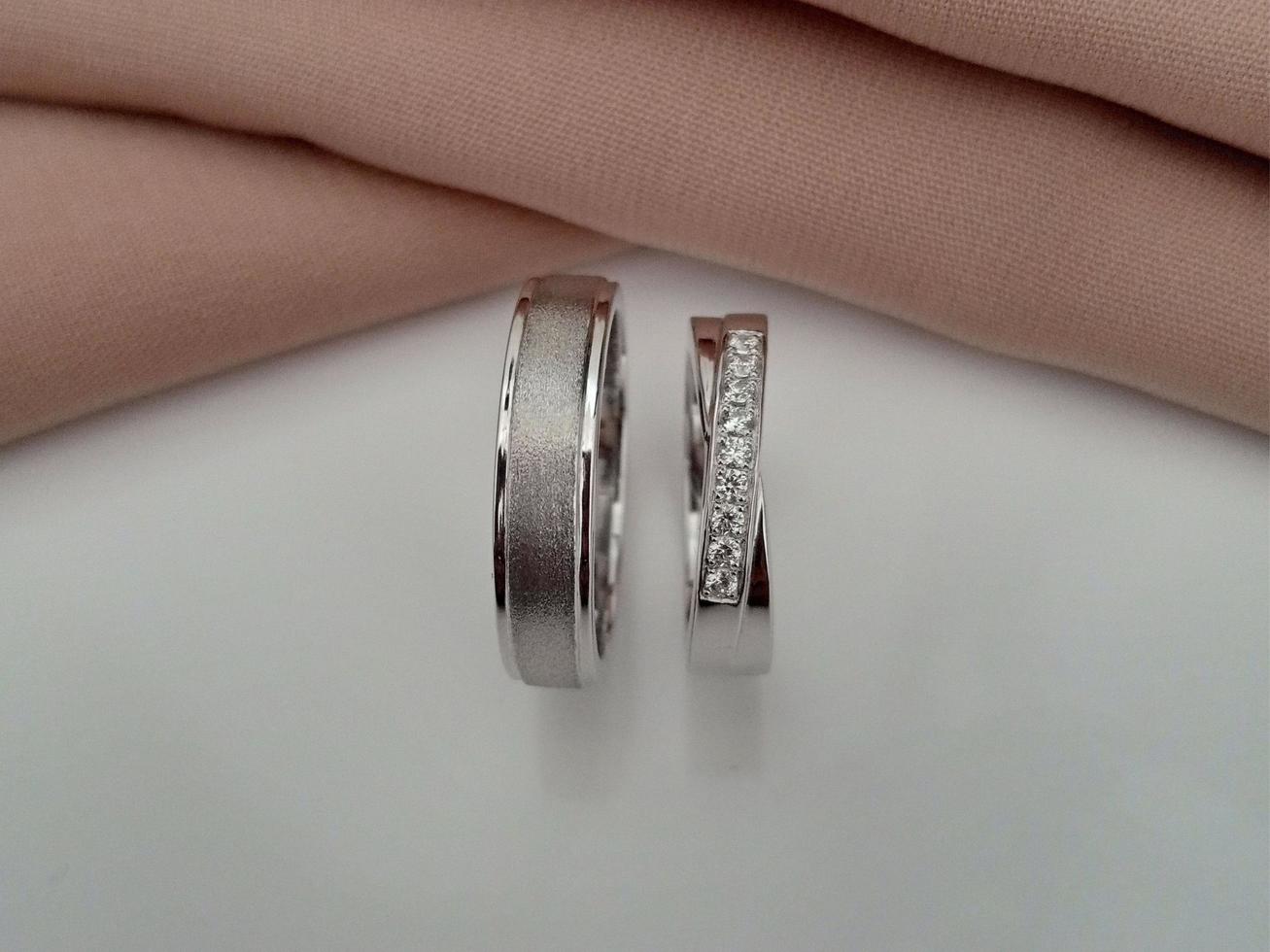 alliance en or blanc. bague couple avec finition brillante et doff avec fond en tissu marron et base blanche photo