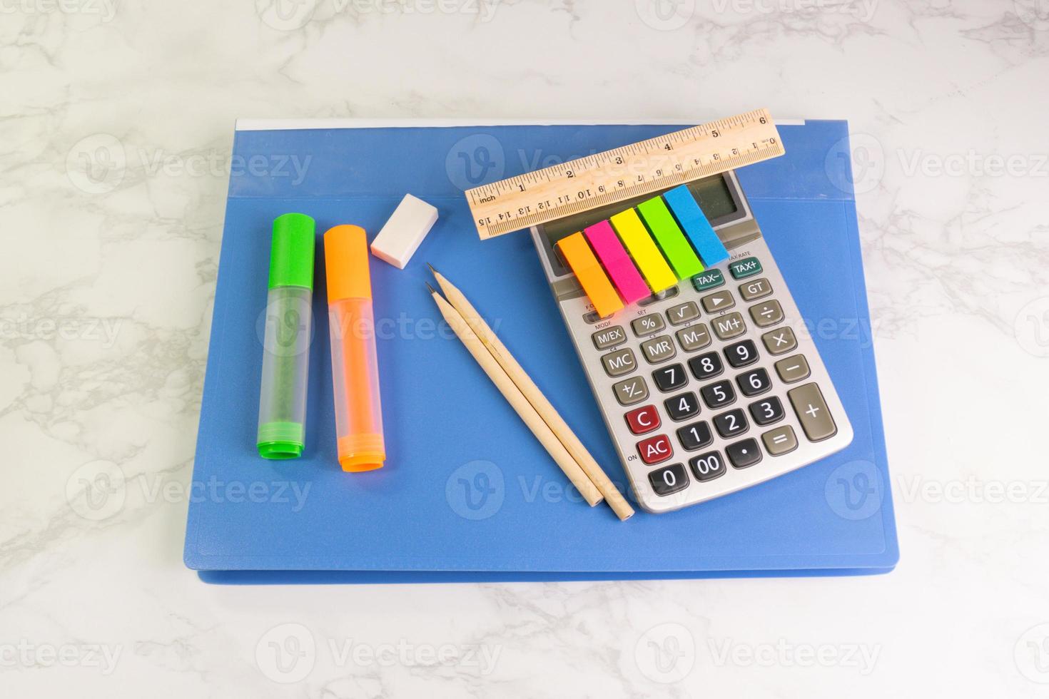 dossier bleu et équipement d'écriture avec calculatrice, surligneur, crayon, règle, gomme sur la table blanche au bureau photo