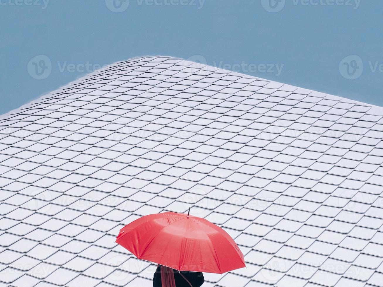 un parapluie rouge contre un toit en bardeaux d'acier blanc dans la ville photo