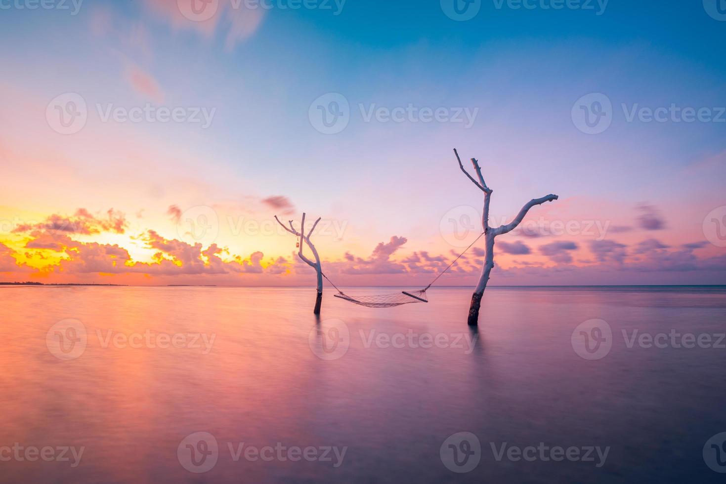 modèle de vacances d'été. coucher de soleil sur le hamac d'eau dans le lagon de la mer tropicale. ciel romantique relaxant avec des nuages colorés, vacances de rêve, concept de couple amour romance. jeté, paysage naturel incroyable photo