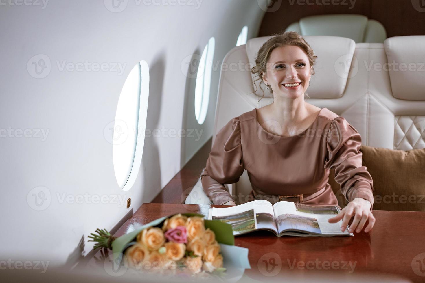 heureuse femme élégante assise dans un avion privé à la fenêtre photo