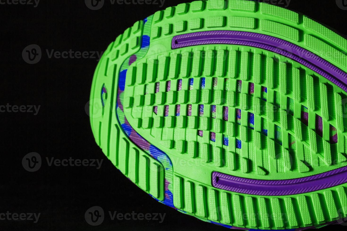 une chaussure de course sportive avec une semelle verte texturée sur fond noir. photo