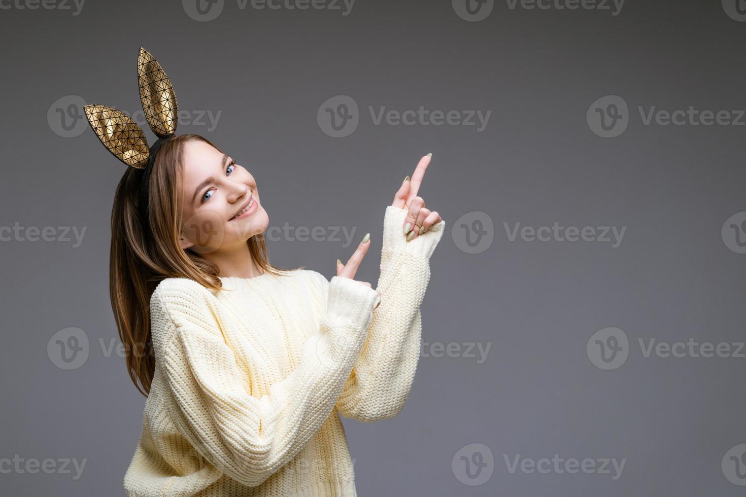 belle jeune femme aux oreilles de lapin montre son doigt à l'arrière-plan photo