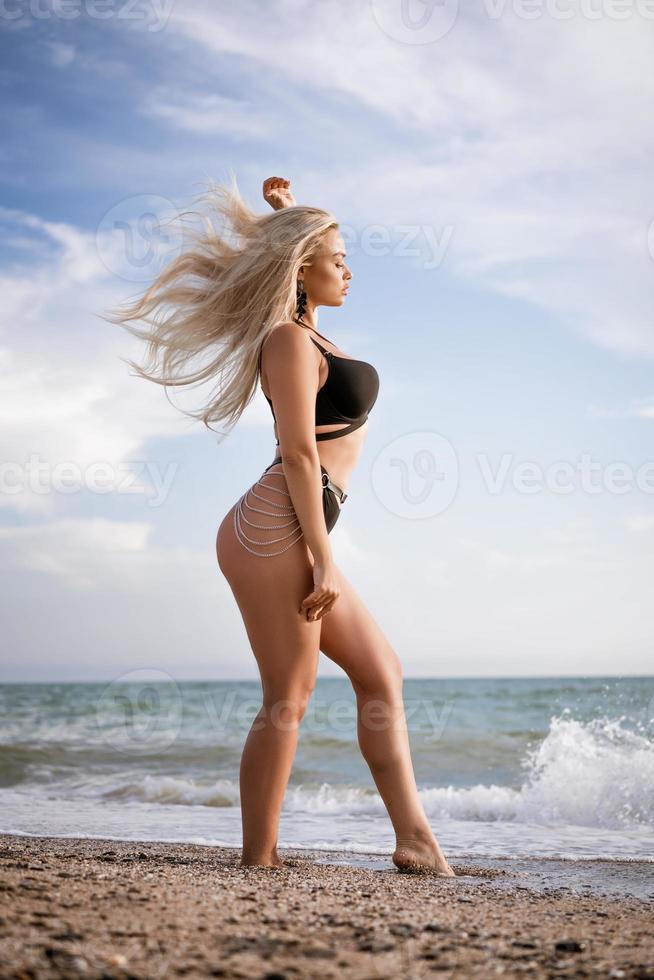 femme mince posant debout sur la plage dans un maillot de bain noir photo