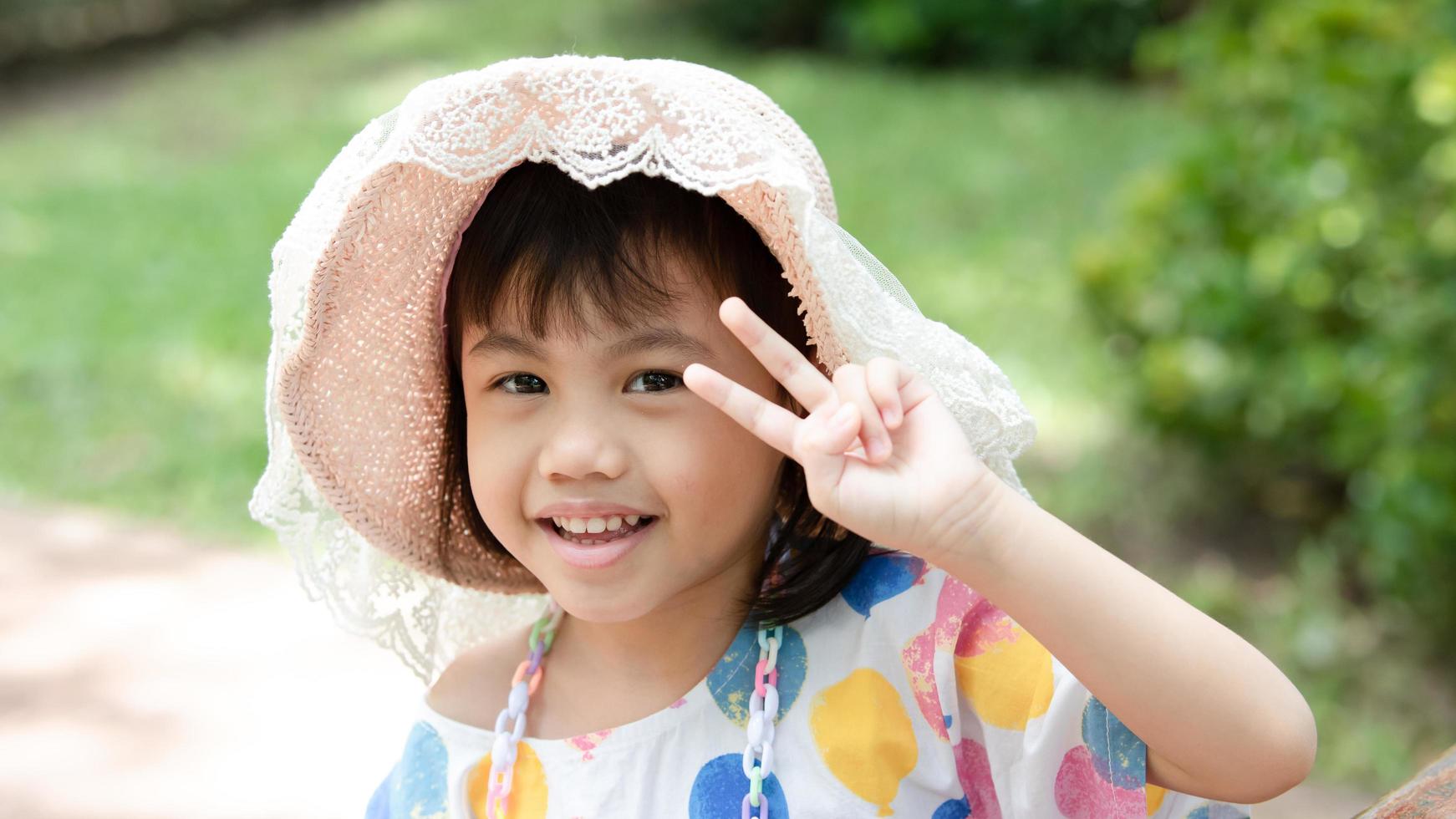 portrait d'heureuse charmante petite fille asiatique de 4 ans, petite fille d'âge préscolaire souriante regardant la caméra montrant 2 doigts avec espace de copie. photo