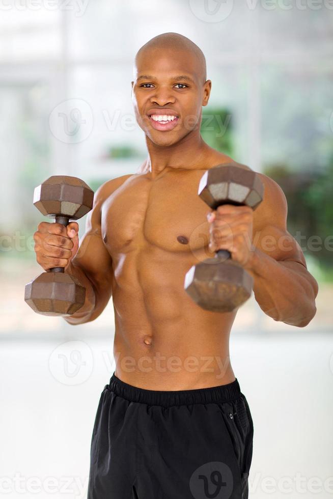 homme afro-américain tenant des haltères dans une salle de sport photo