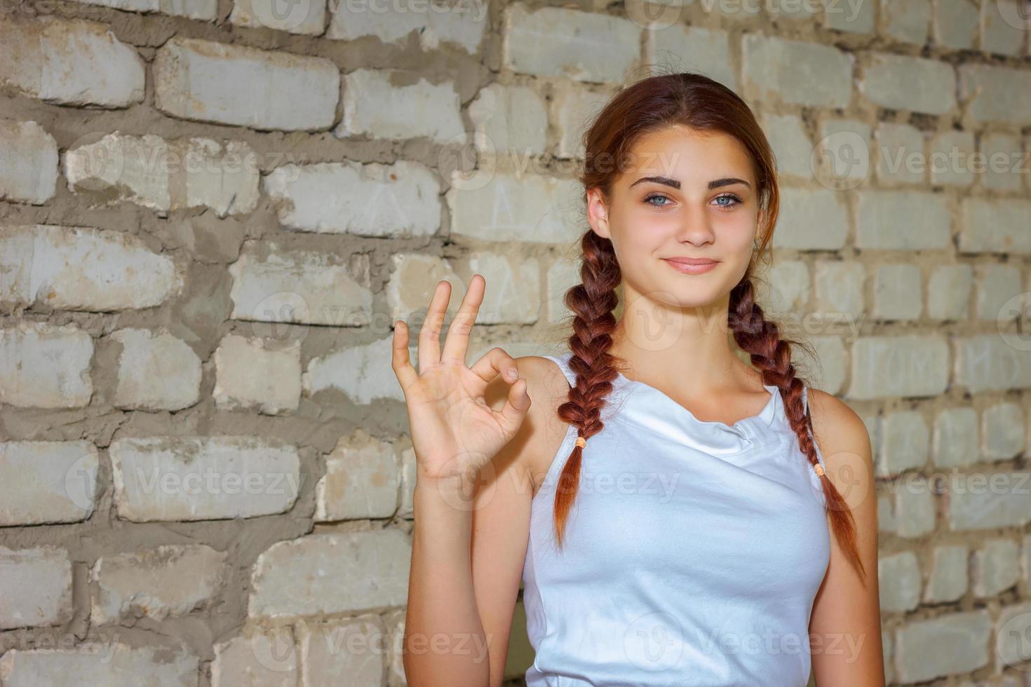 belle jeune fille souriante avec bonheur sur fond de mur de briques photo