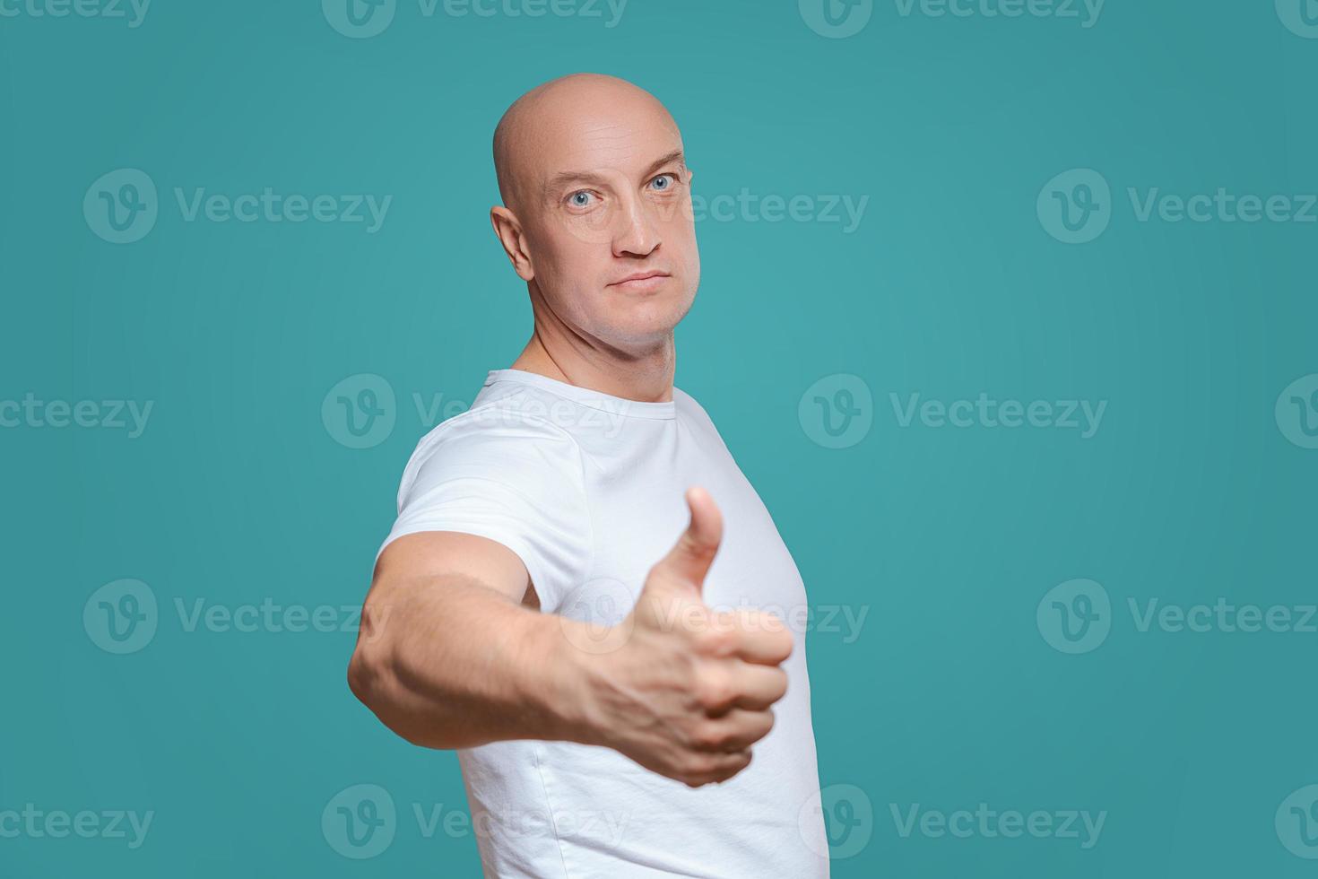 un homme émotif dans un t-shirt blanc montre d'un geste de la main que tout est cool, sur un fond de titian photo