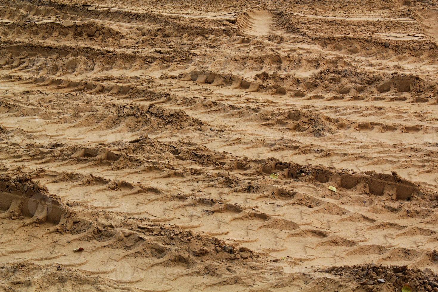 forme de lignes de marque de trace de pneu sur fond de sable sec. empreinte de pneu de trail de machinerie lourde. forme du véhicule. concept de toile de fond de chantier de construction de route. trace de motif de roue sur la boue. texture naturelle. photo