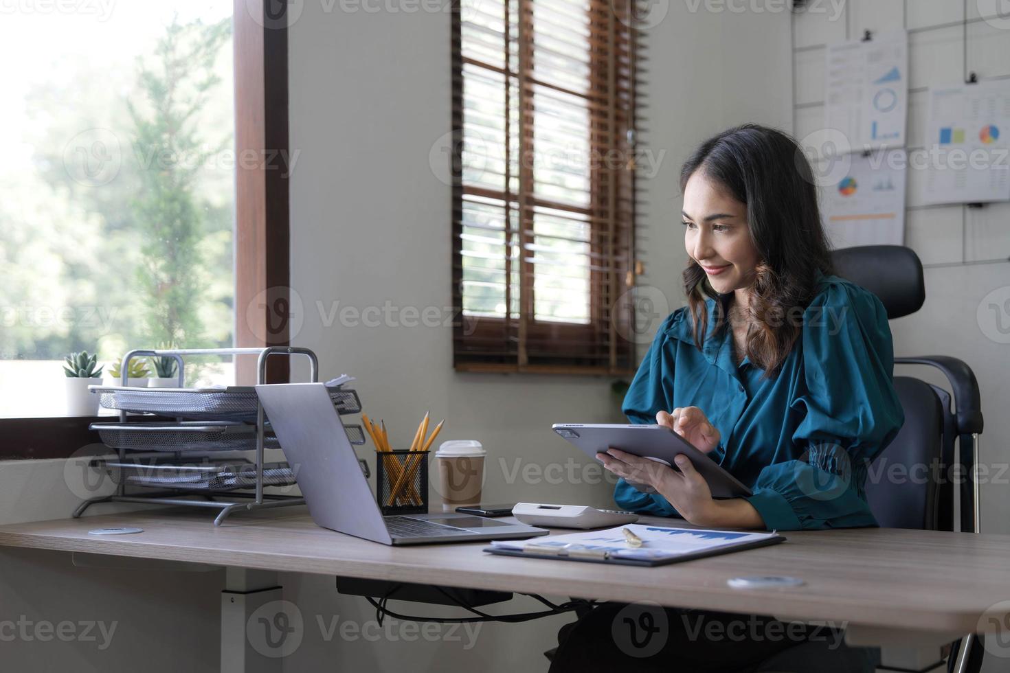 jeune femme d'affaires asiatique travaille sur tablette avec ordinateur portable au bureau. photo