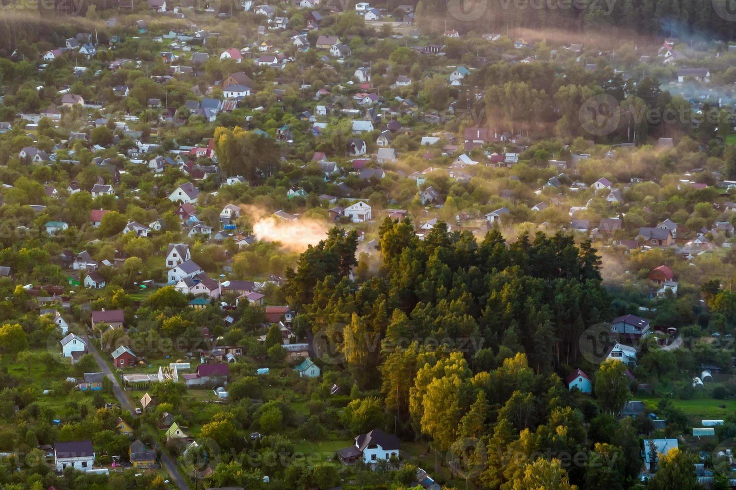 vue panoramique aérienne du village verdoyant avec homestads, maisons, granges et route de gravier en forêt photo