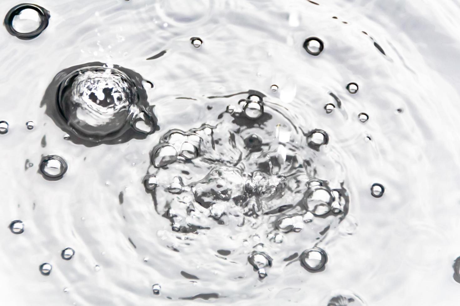 des gouttelettes d'eau ou des perles d'eau tombent à la surface de l'eau, provoquant la dispersion et la mousse de la surface de l'eau. photo