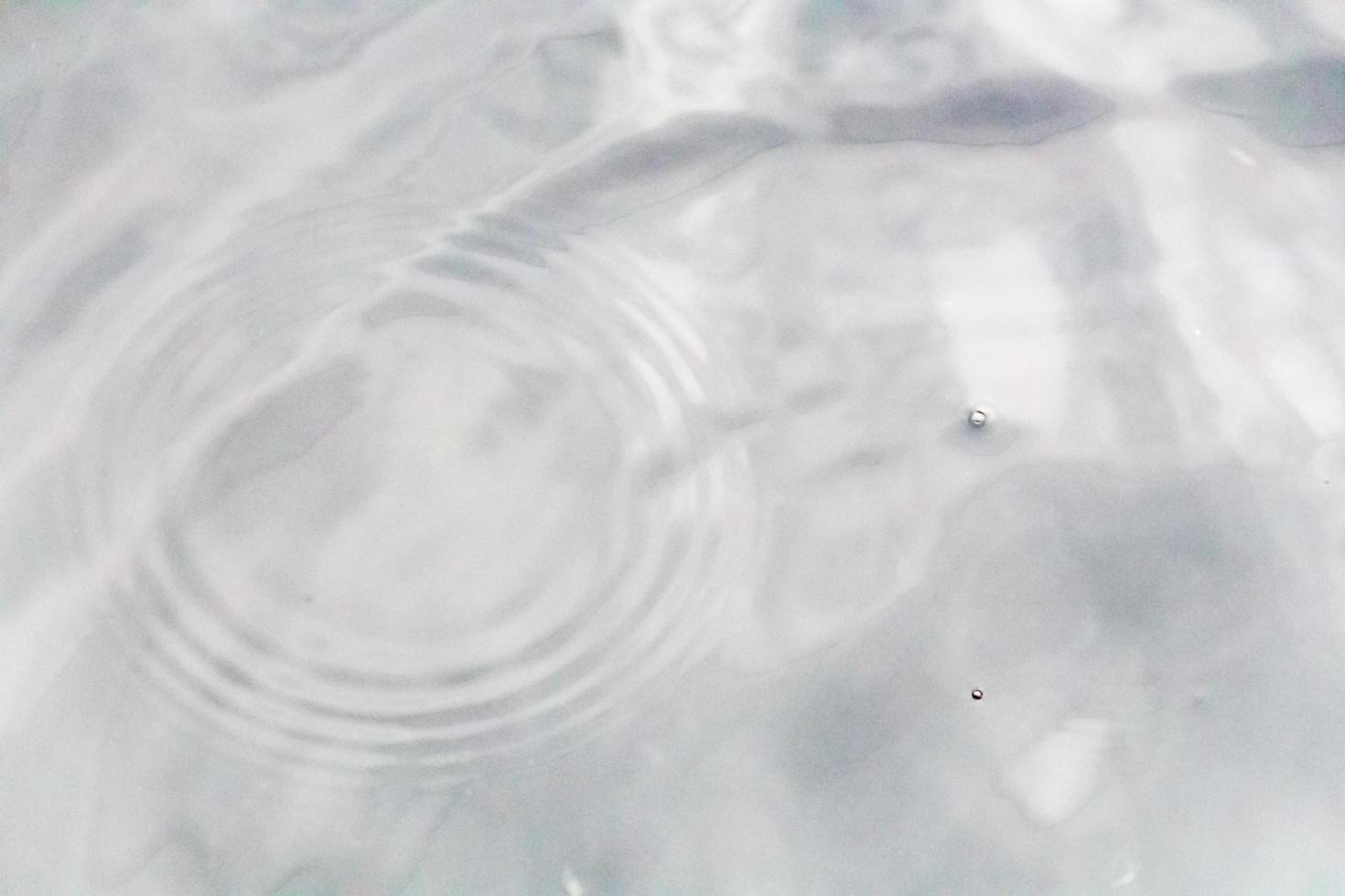 des gouttelettes d'eau ou des perles d'eau tombent à la surface de l'eau, provoquant la dispersion et la mousse de la surface de l'eau. photo