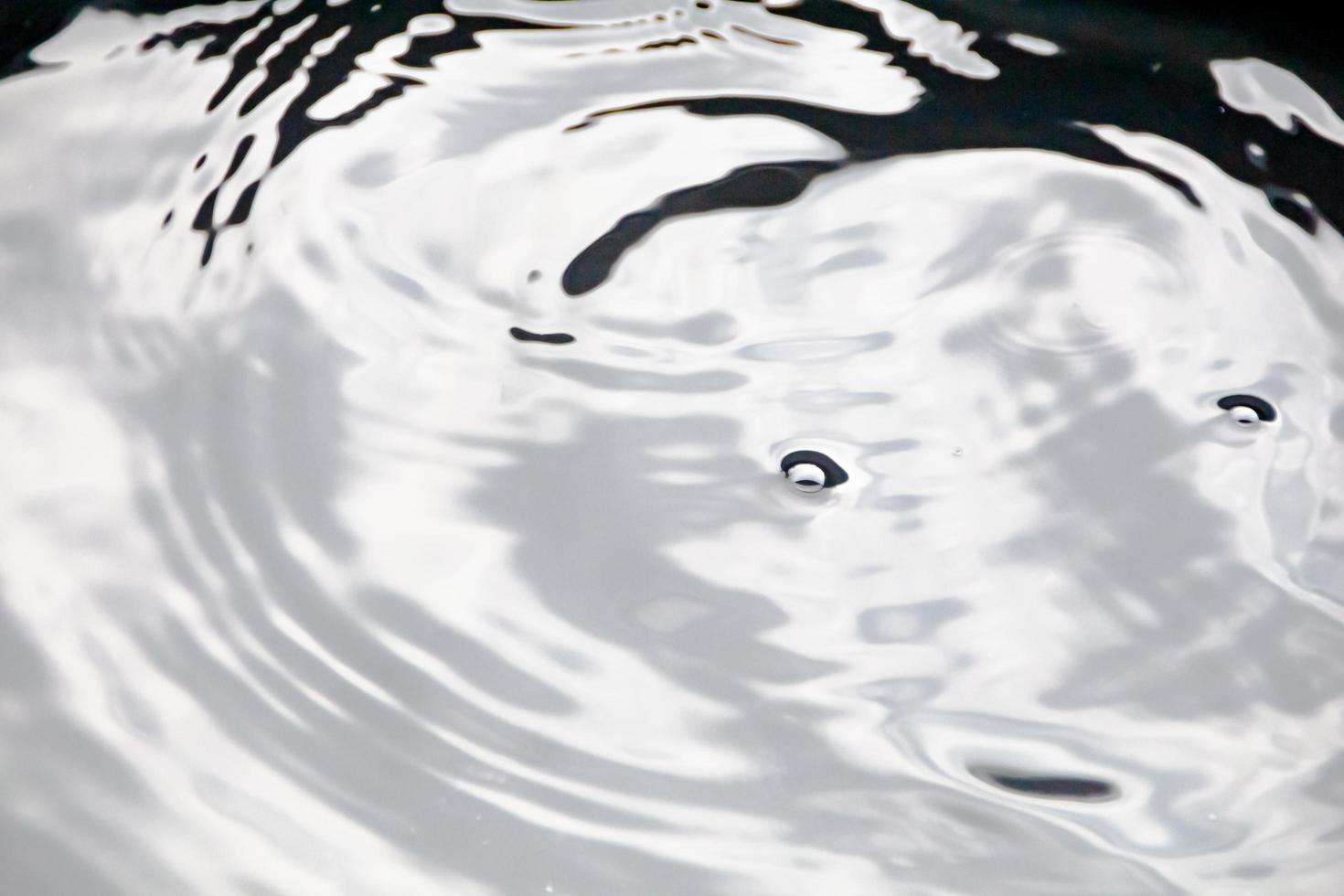 des gouttelettes d'eau ou des perles d'eau tombent à la surface de l'eau, provoquant la dispersion et la mousse de la surface de l'eau. photo