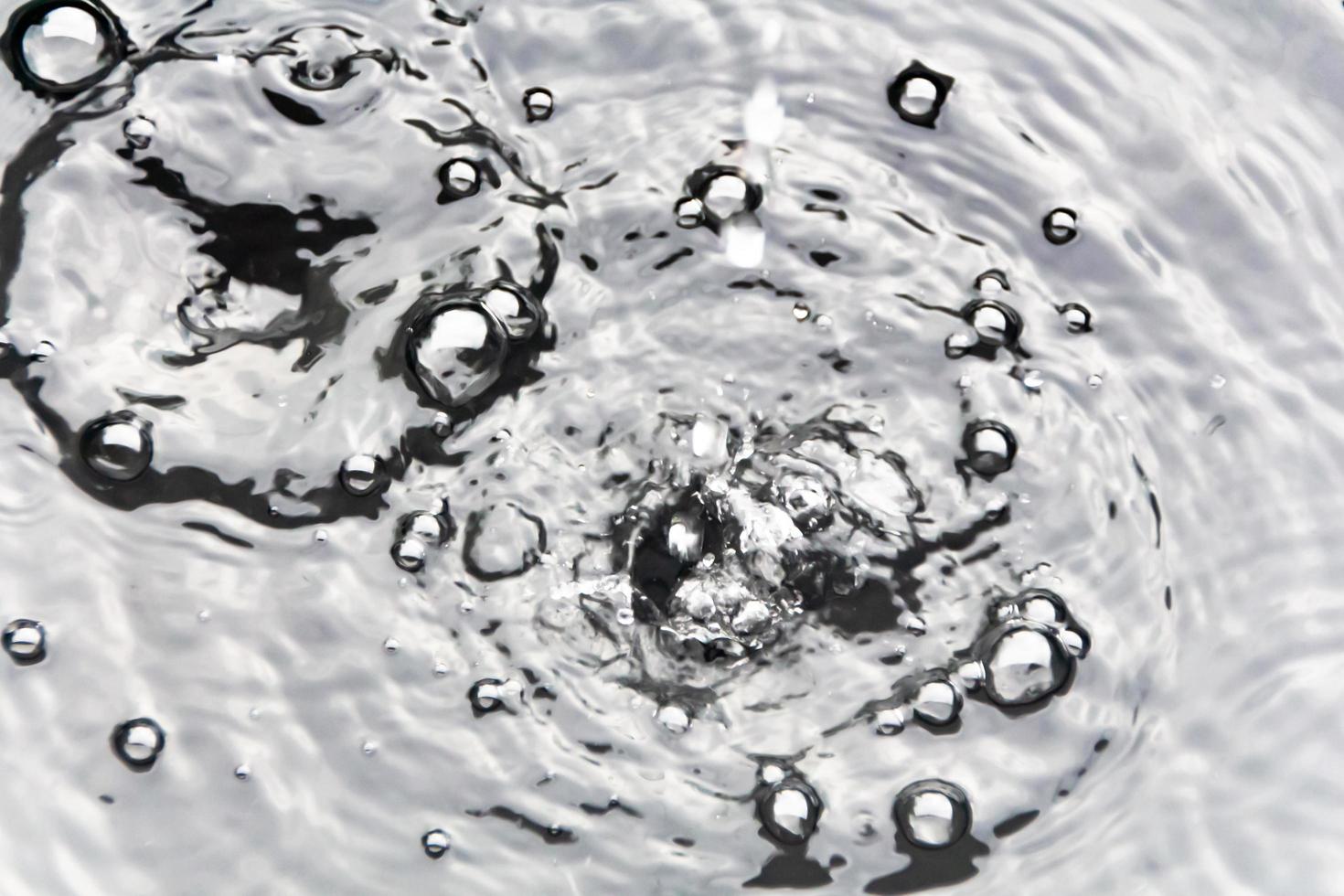 des gouttelettes d'eau ou des perles d'eau tombent à la surface de l'eau, provoquant la dispersion et la mousse de la surface de l'eau. photo