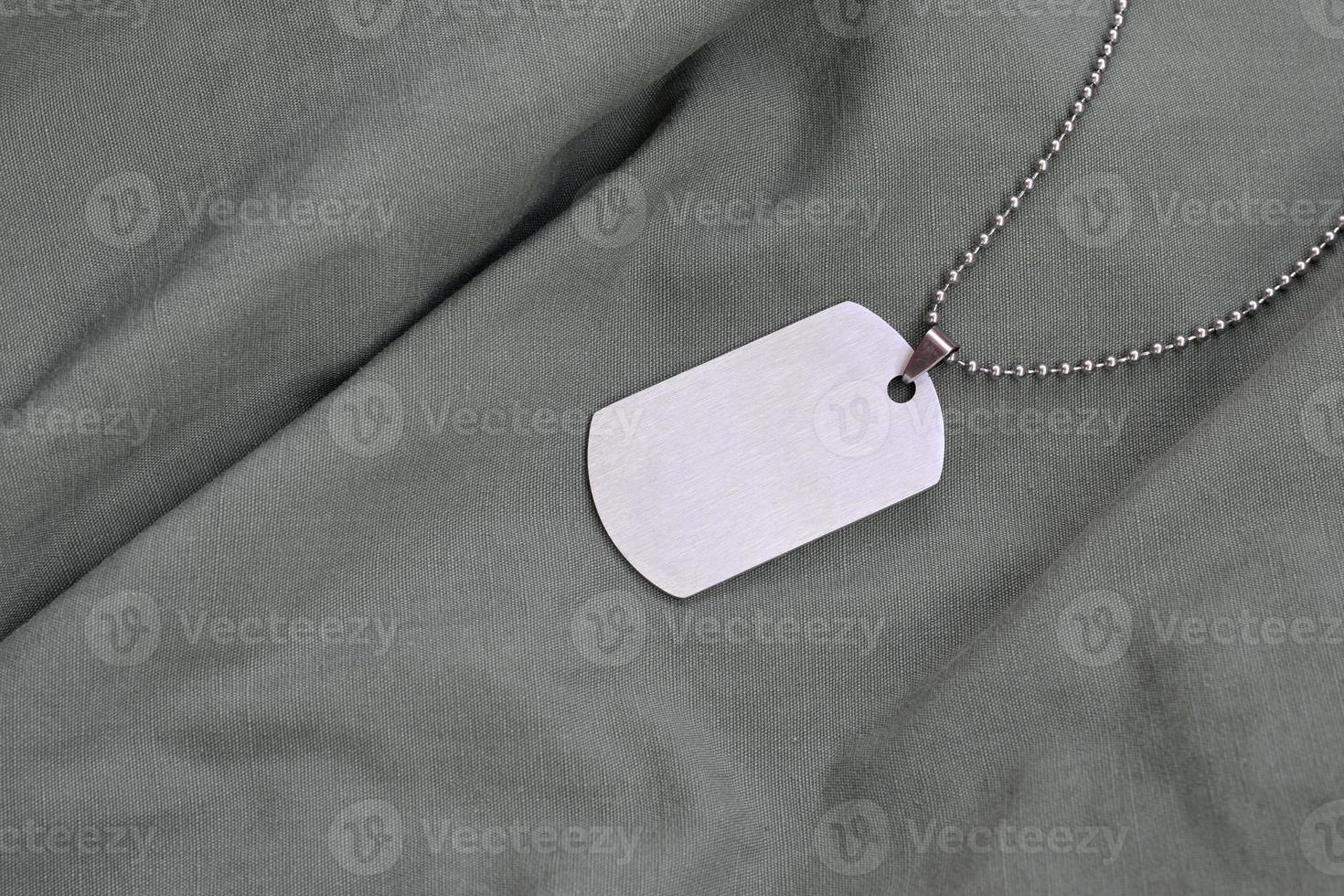 Perles militaires argentées avec dog tag sur uniforme de fatigue vert foncé photo