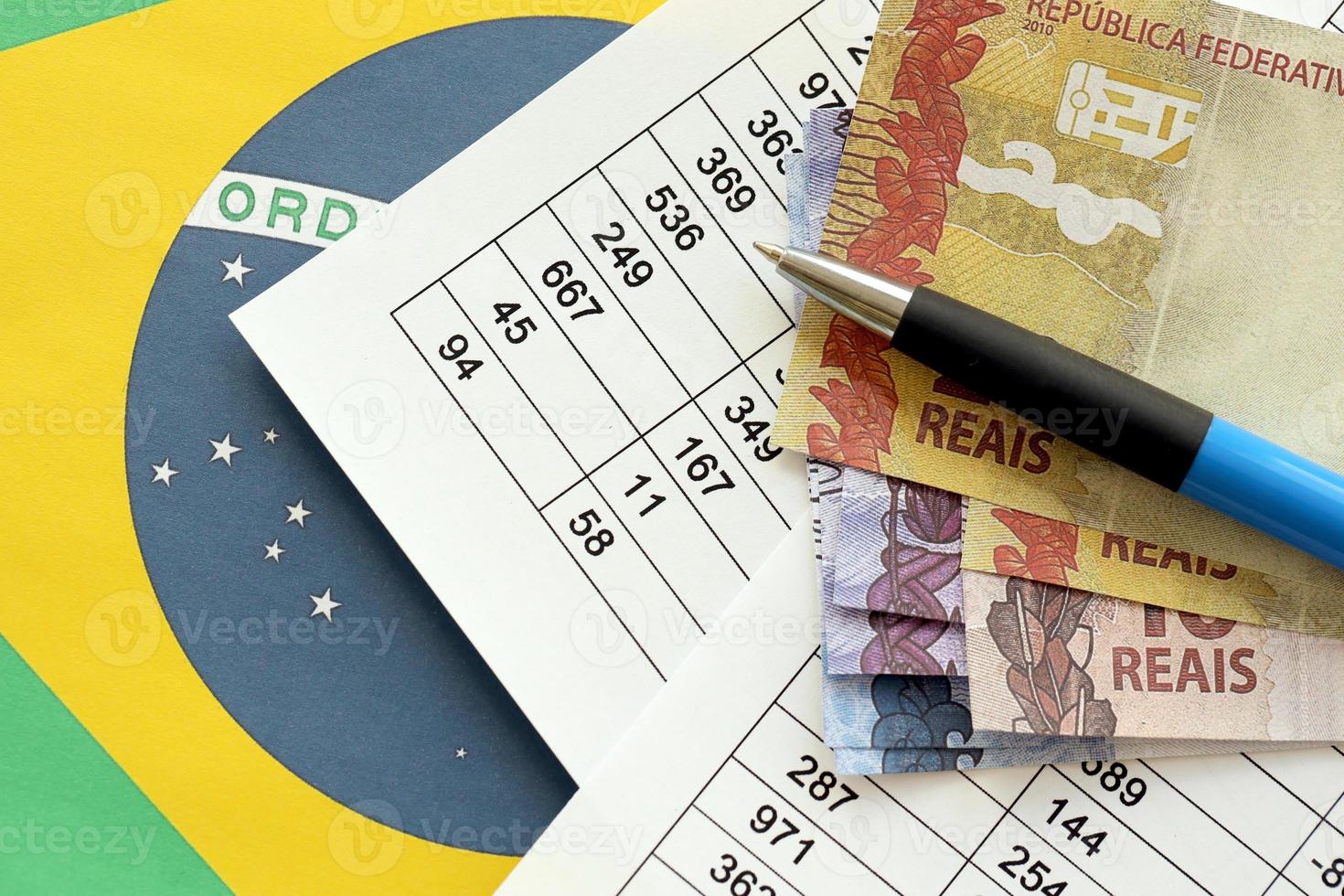 stylo avec des billets d'argent brésiliens sur blanc de jeu de loterie. concept de chance et de jeu au brésil photo