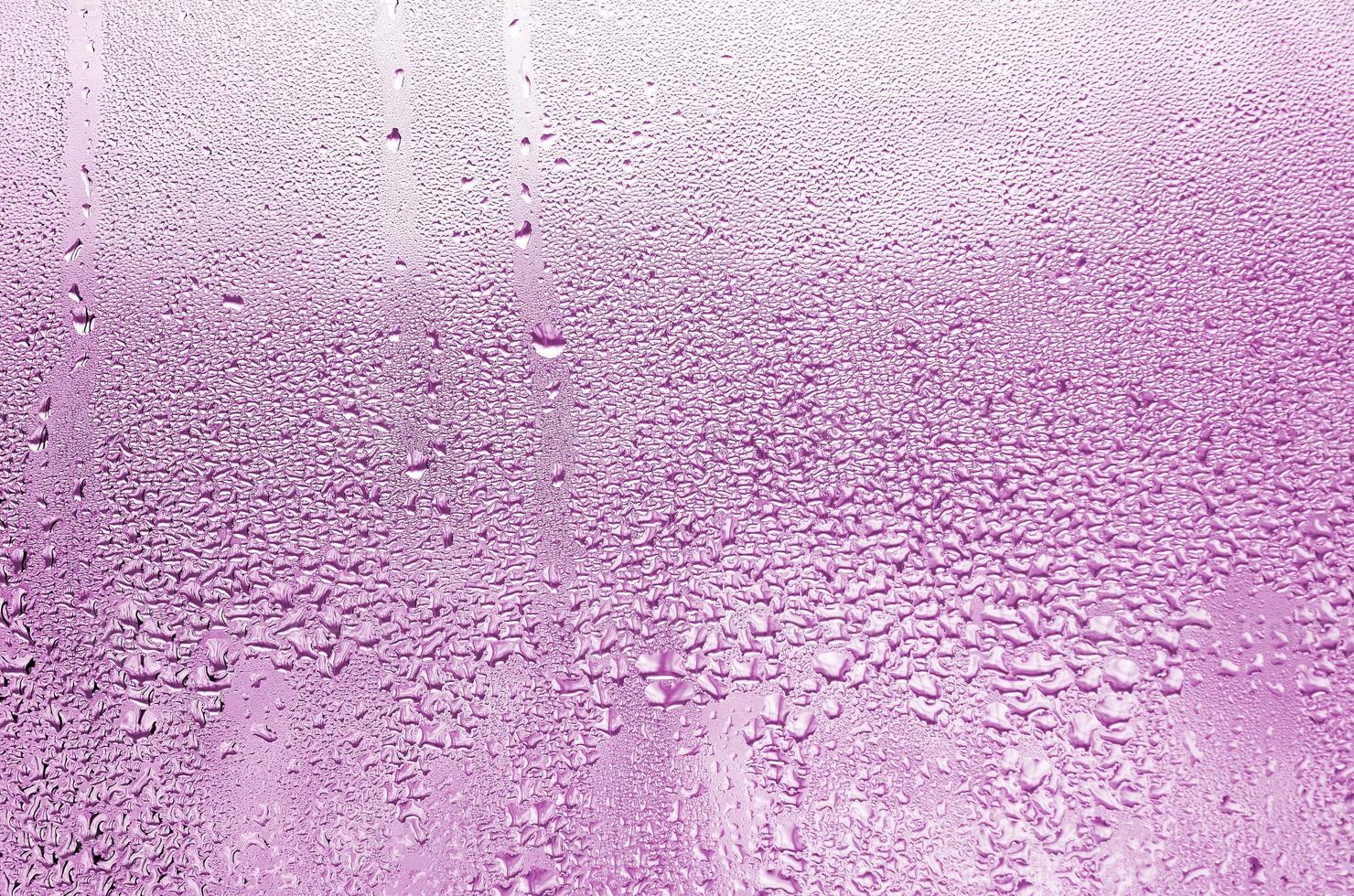 texture d'une goutte de pluie sur un fond transparent en verre humide. tonique en couleur rose photo